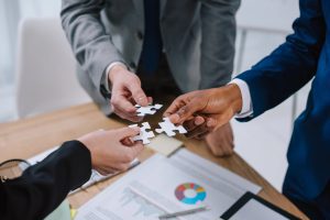 Tres ejecutivos tratando de unir tres piezas de rompecabezas