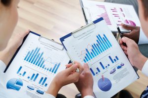 Hombre y mujer analizando gráficos estadísticos mientras rosan sus manos