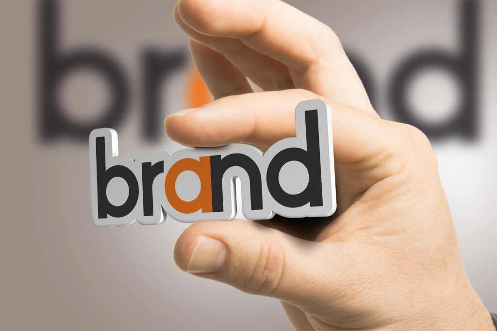 Mano que muestra la palabra "Brand" forjada en una pieza de plantico 3D